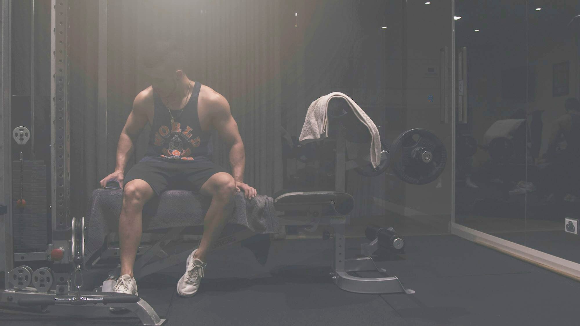 Someone sitting on a bench in a dark gym after training
